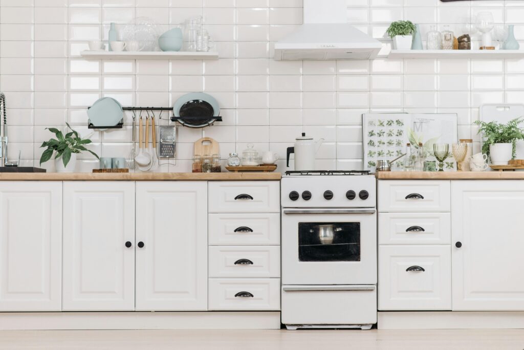 Bright minimalist kitchen with white cabinets and stove, offering a clean and organized look.